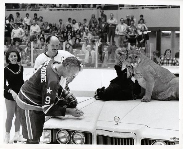 Houston Aeros Gordie Howe signs the hood of a 1973 Mercury Cougar at a WHA game