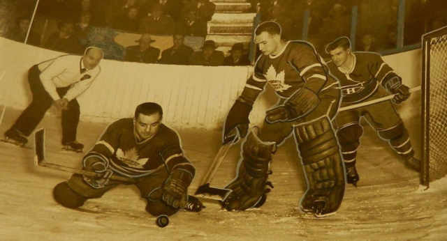 Bill Juzda clears the puck in front of Al Rollins, as Ken Mosdell looks on 1950