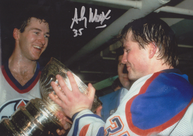 Andy Moog is about to drink from the Stanley Cup, as Kevin Lowe holds it 1984